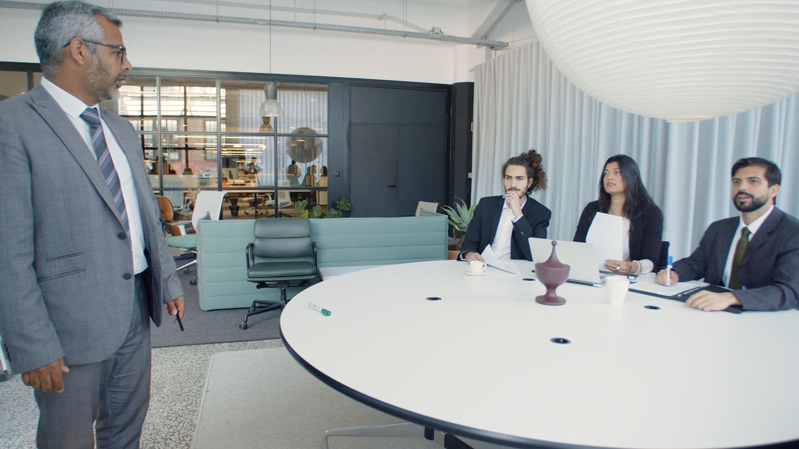 Executives in a bright glass conference room discussing strategy